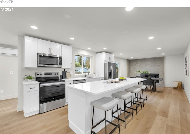 kitchen with sink, a center island, light hardwood / wood-style floors, white cabinets, and appliances with stainless steel finishes