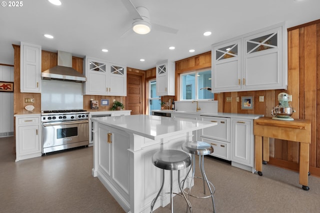 1209 N Prom, Seaside, OR 97138 - kitchen featuring wall chimney range hood, stainless steel range, light countertops, white cabinets, and ceiling fan