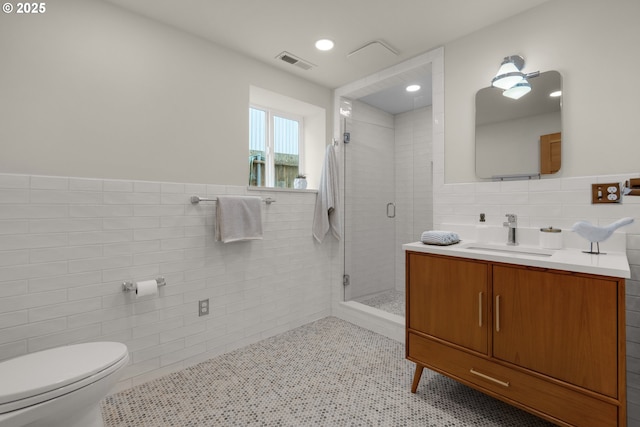 1209 N Prom, Seaside, OR 97138 - full bathroom with tile walls, toilet, vanity, a stall shower, and wainscoting