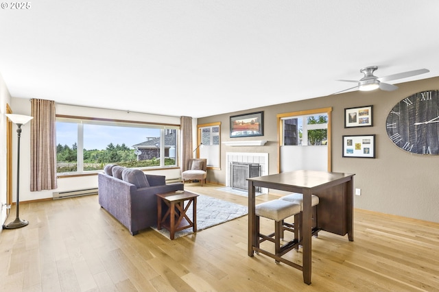 2801 Willows Rd Unit 1, Seaview, WA 98644 - living area with baseboard heating, a tile fireplace, light wood finished floors, and ceiling fan