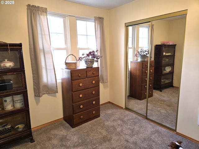 carpeted bedroom with a closet, multiple windows, and baseboards