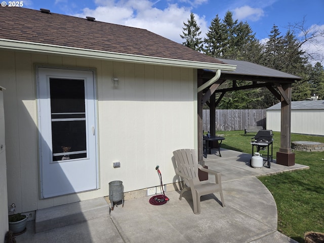 view of patio with an outdoor structure, fence, and a gazebo