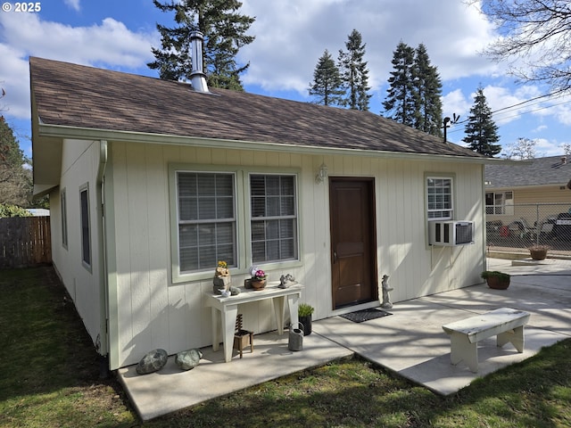 rear view of house with a shingled roof, cooling unit, fence, and a patio