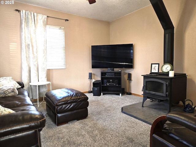 living area with carpet floors, a ceiling fan, a wood stove, a textured ceiling, and baseboards