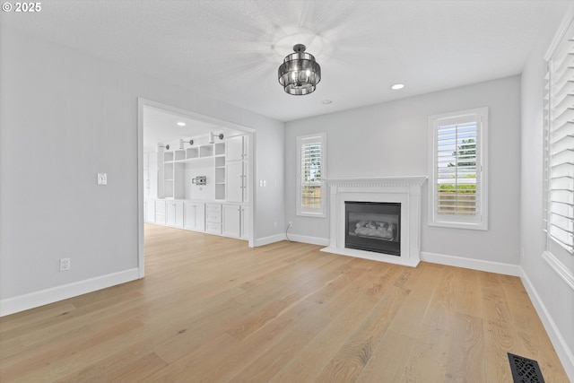 19338 Inishbride Ct, Oregon City, OR 97045 - unfurnished living room featuring a glass covered fireplace, light wood-style floors, a chandelier, and recessed lighting