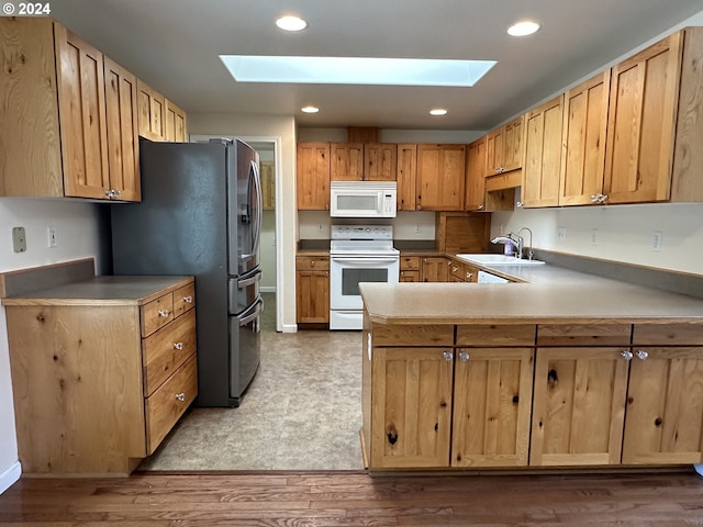 2175 23rd St, Florence, OR 97439 - kitchen featuring white appliances, a skylight, a sink, and a peninsula