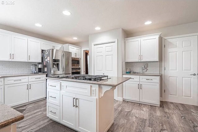 715 Shadowwood Loop, Keizer, OR 97303 - kitchen featuring appliances with stainless steel finishes, a kitchen island, white cabinets, decorative backsplash, and recessed lighting