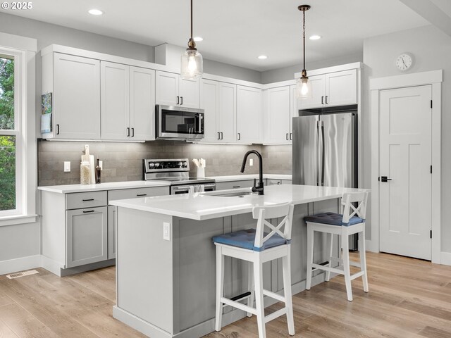 37330 Labiske Ln, Astoria, OR 97103 - kitchen with stainless steel appliances, backsplash, a sink, a breakfast bar area, and light wood-style flooring