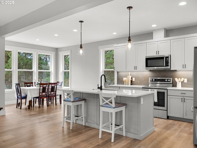 37330 Labiske Ln, Astoria, OR 97103 - kitchen featuring stainless steel appliances, a sink, light countertops, decorative backsplash, and a kitchen island with sink