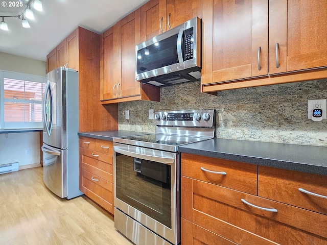 213 Oswego, Lake Oswego, OR 97035 - kitchen featuring appliances with stainless steel finishes, brown cabinetry, light wood-style flooring, decorative backsplash, and dark countertops