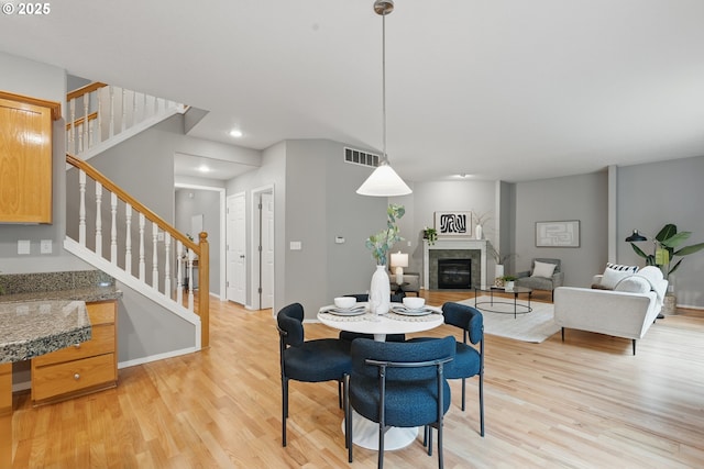 555 NE 58th Ave, Hillsboro, OR 97124 - dining space featuring light wood-style flooring, stairs, a glass covered fireplace, baseboards, and recessed lighting