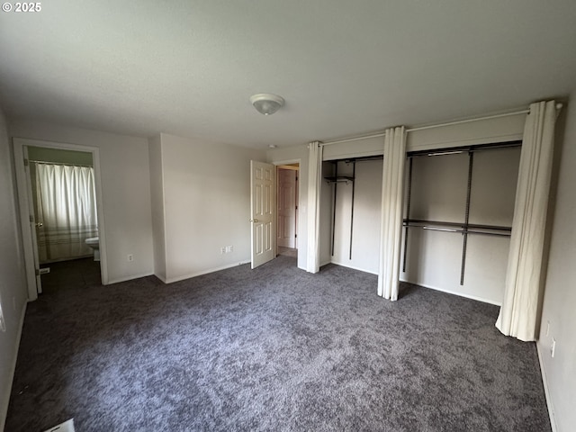 unfurnished bedroom featuring dark carpet, multiple closets, and ensuite bathroom