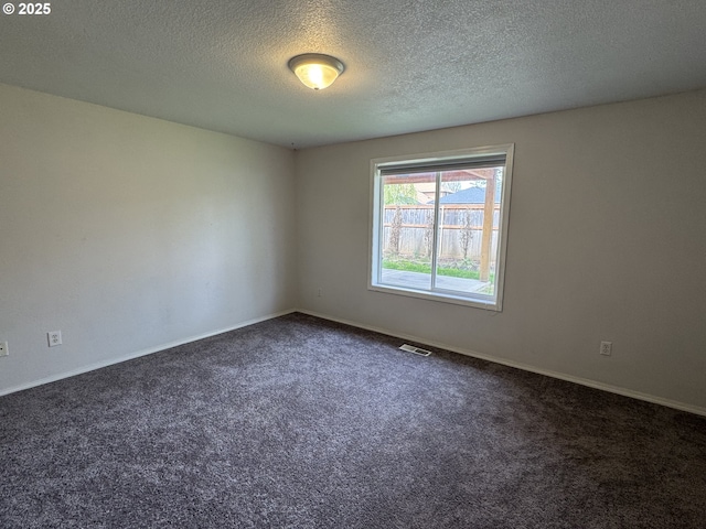 unfurnished room with visible vents, baseboards, dark colored carpet, and a textured ceiling