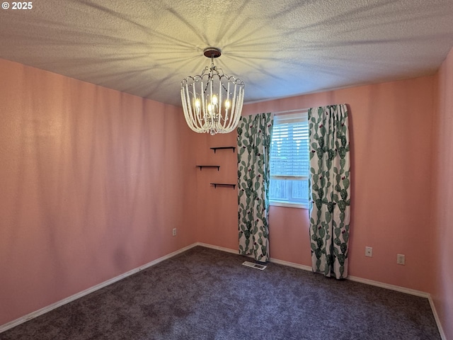 spare room with a notable chandelier, baseboards, a textured ceiling, visible vents, and dark carpet