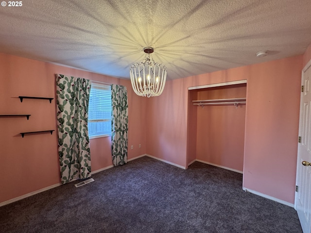 unfurnished bedroom featuring visible vents, carpet flooring, a notable chandelier, and a textured ceiling