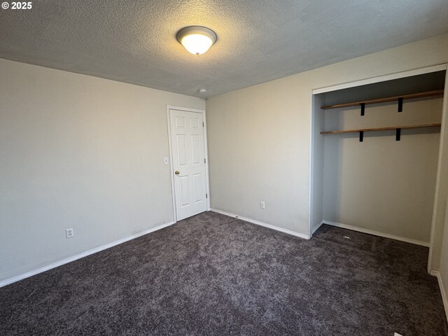 unfurnished bedroom with a closet, baseboards, dark colored carpet, and a textured ceiling