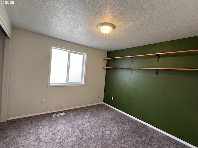 unfurnished bedroom featuring a textured ceiling, a closet, visible vents, carpet flooring, and baseboards