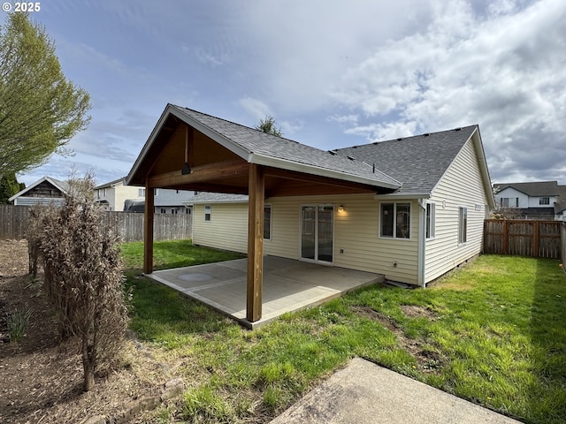 rear view of property featuring a fenced backyard, a shingled roof, a patio, and a lawn