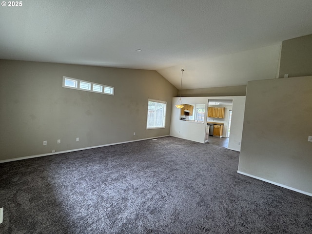 unfurnished living room with dark carpet, a textured ceiling, baseboards, and lofted ceiling