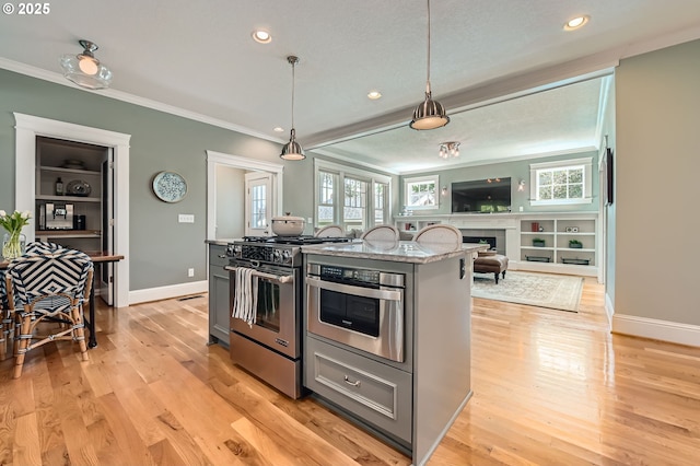 kitchen featuring crown molding, open floor plan, appliances with stainless steel finishes, and baseboards