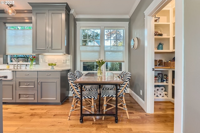 dining space with baseboards, ornamental molding, and light wood-type flooring