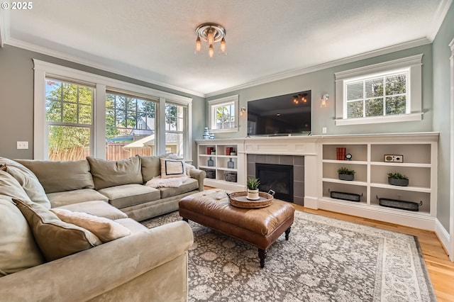 living room with crown molding, wood finished floors, and a tile fireplace