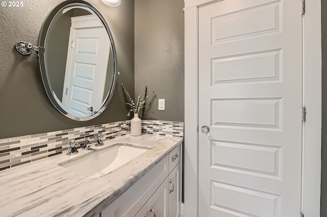 bathroom with vanity, decorative backsplash, and a textured wall