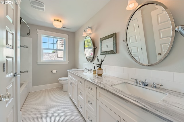 bathroom with a sink, double vanity, toilet, baseboards, and visible vents