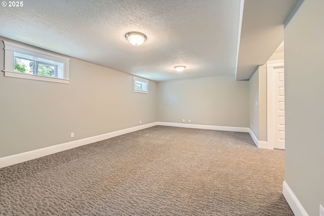 basement with baseboards, carpet flooring, and a textured ceiling