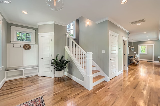 stairs with crown molding, recessed lighting, visible vents, and wood finished floors