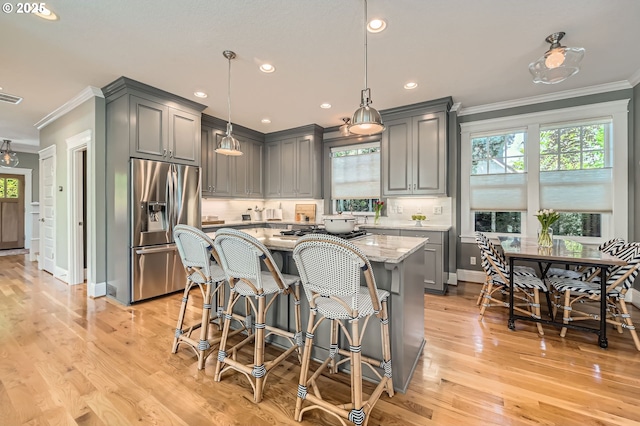 kitchen featuring crown molding, a wealth of natural light, and stainless steel fridge with ice dispenser