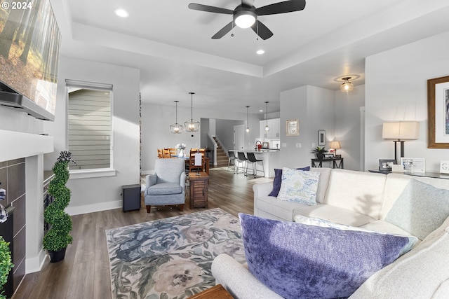 living room featuring a tray ceiling, ceiling fan, and dark hardwood / wood-style floors