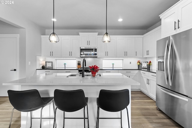 kitchen with white cabinets, pendant lighting, sink, and appliances with stainless steel finishes