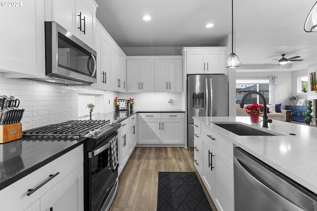 kitchen with white cabinets, appliances with stainless steel finishes, pendant lighting, and sink