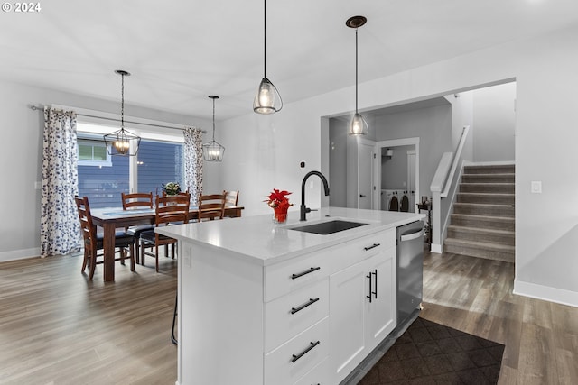 kitchen featuring dishwasher, a kitchen island with sink, white cabinets, sink, and decorative light fixtures