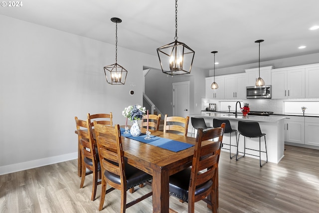 dining area with light hardwood / wood-style floors, sink, and an inviting chandelier