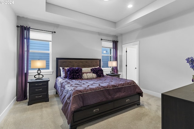 bedroom with light carpet and a tray ceiling