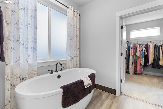 bathroom featuring a tub to relax in, a wealth of natural light, and hardwood / wood-style flooring