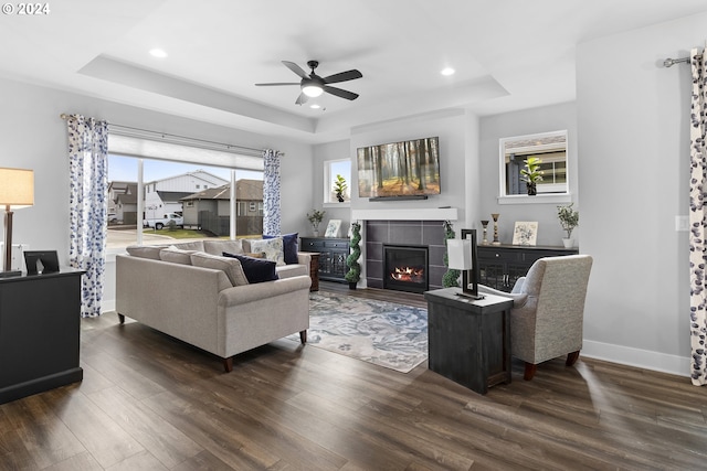 living room with ceiling fan, dark hardwood / wood-style flooring, and a tray ceiling