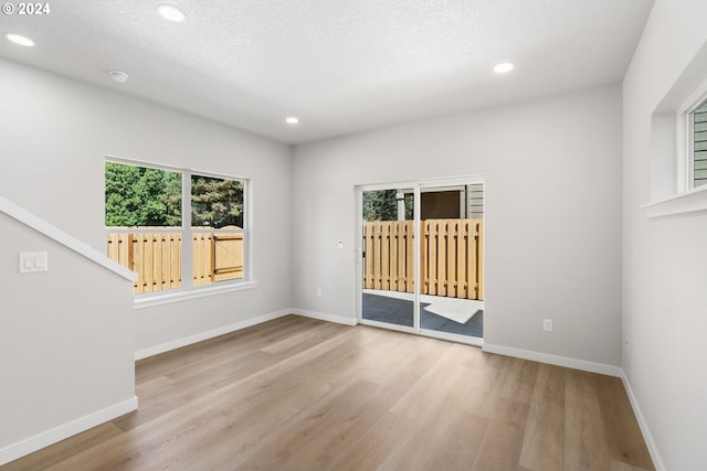 unfurnished room featuring a textured ceiling and light hardwood / wood-style floors