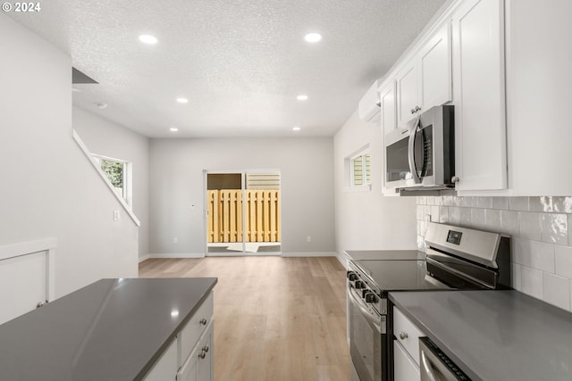 kitchen featuring stainless steel appliances, a textured ceiling, tasteful backsplash, and white cabinetry