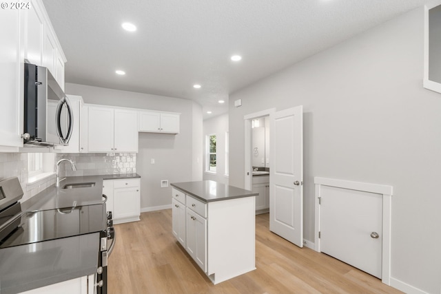 kitchen with sink, a center island, white cabinetry, and appliances with stainless steel finishes