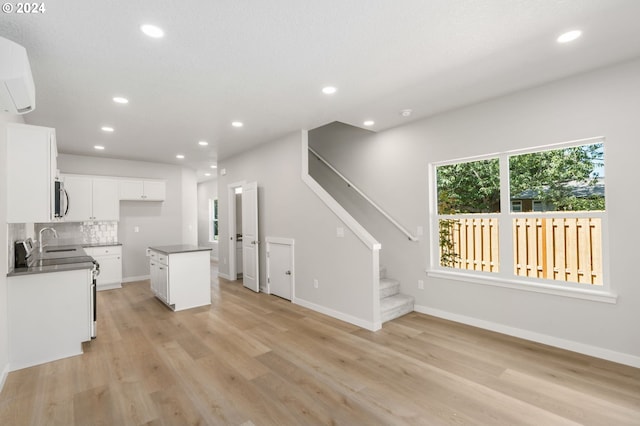 kitchen featuring stainless steel appliances, decorative backsplash, a kitchen island, white cabinetry, and sink