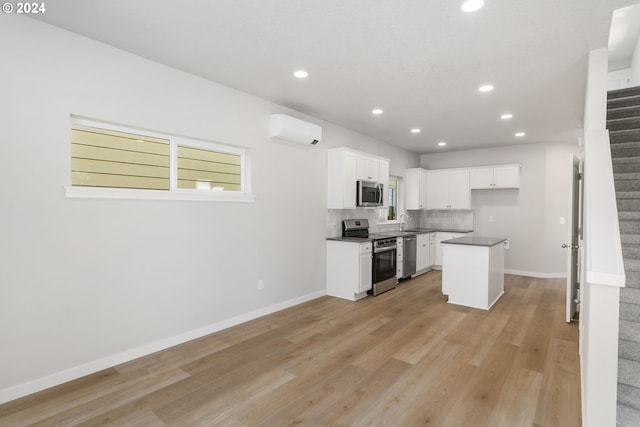 kitchen featuring white cabinetry, appliances with stainless steel finishes, a wall mounted air conditioner, a kitchen island, and light hardwood / wood-style flooring