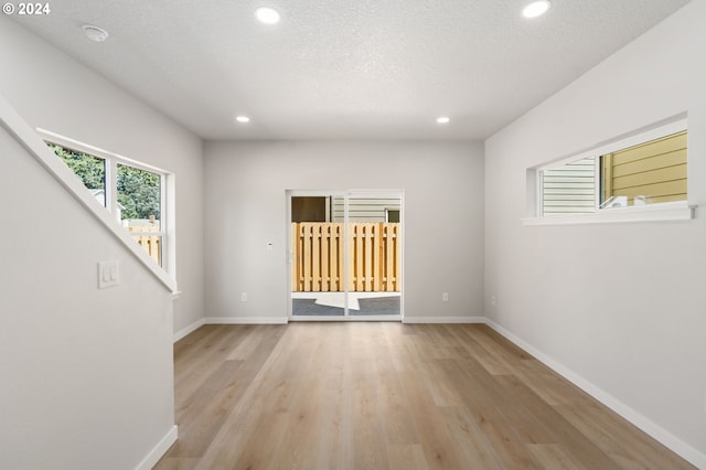 spare room featuring a textured ceiling and light hardwood / wood-style flooring