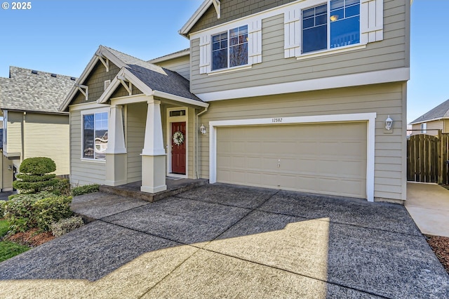 view of front of house with driveway, a garage, and fence
