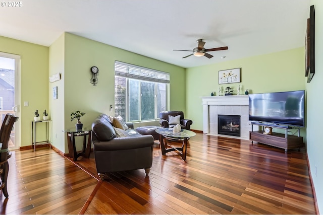 living room with a tile fireplace, hardwood / wood-style floors, and a ceiling fan