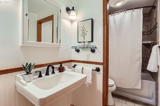 full bathroom featuring toilet, wooden walls, tile patterned floors, shower / tub combo, and sink