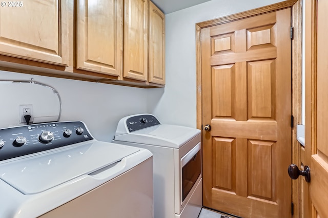 washroom with washing machine and dryer, tile patterned floors, and cabinets