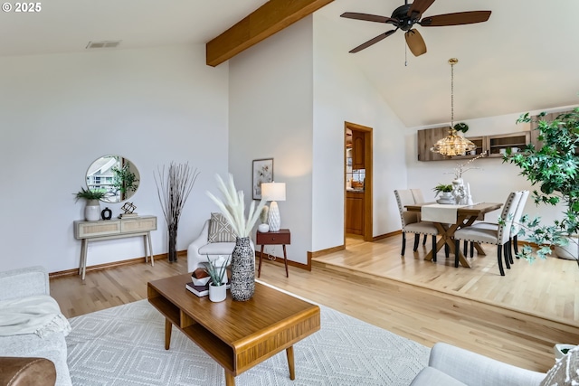 living room with ceiling fan with notable chandelier, high vaulted ceiling, light hardwood / wood-style flooring, and beamed ceiling